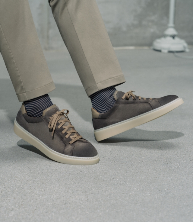 A man wears the Rio Grey Suede with striped black and white socks and tan pants.