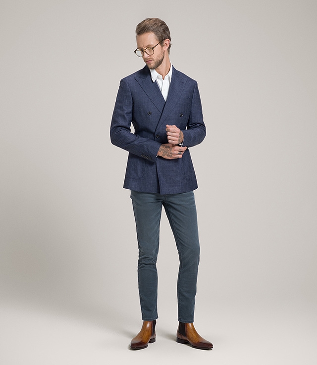 A male model in teal pants and blue suit jacket wears Magnanni Shaw boots in Cuero.