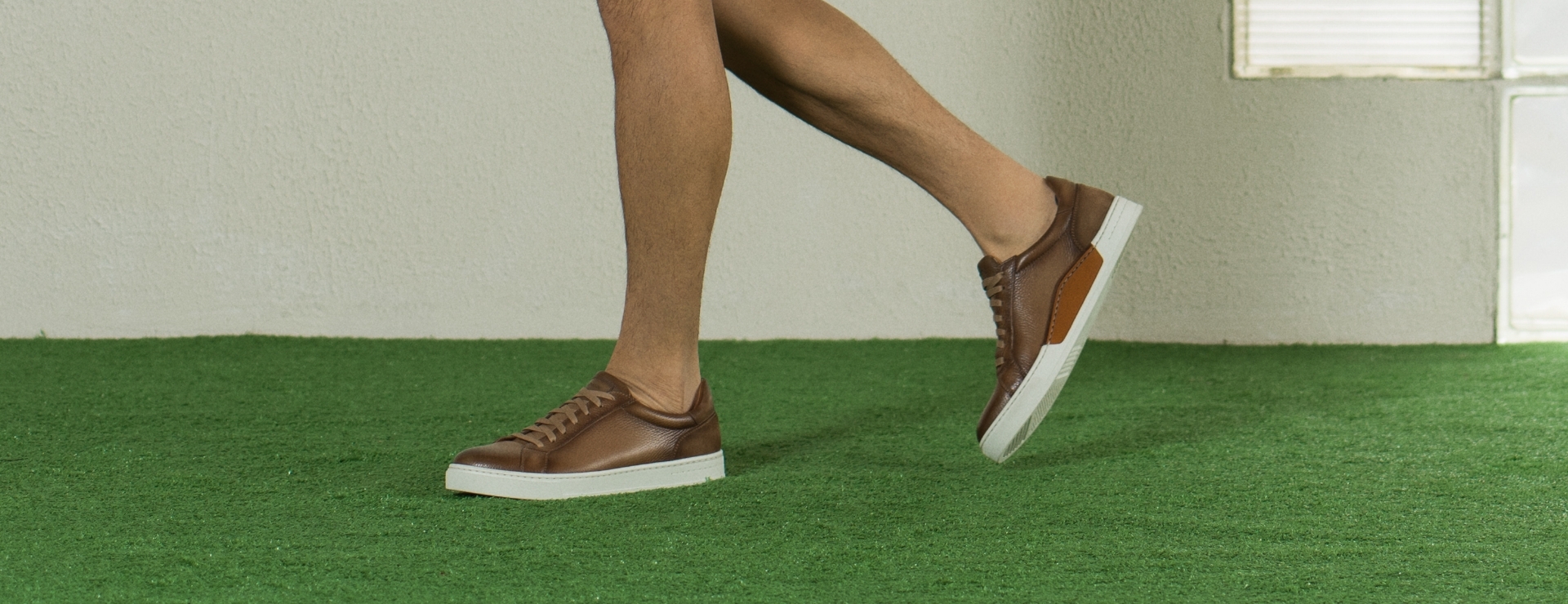 A woman steps takes a step on turf while wearing Magnanni Theresa sneakers.