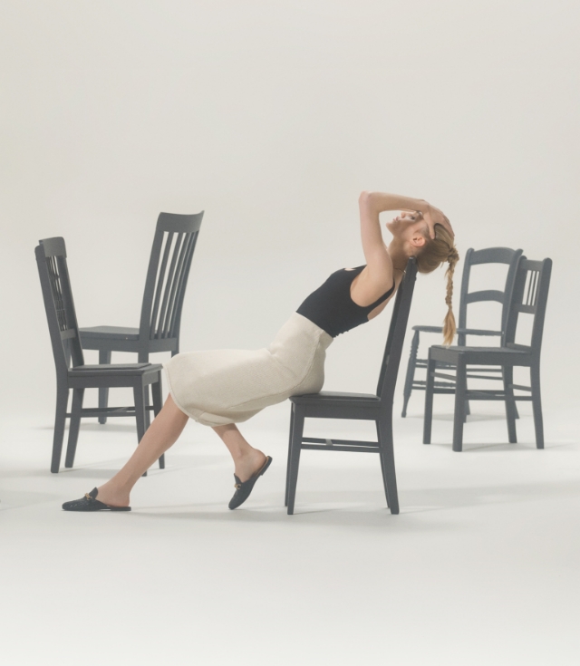 A woman poses on a chair in a black top, white skirt, and Magnanni Carmen II loafers.