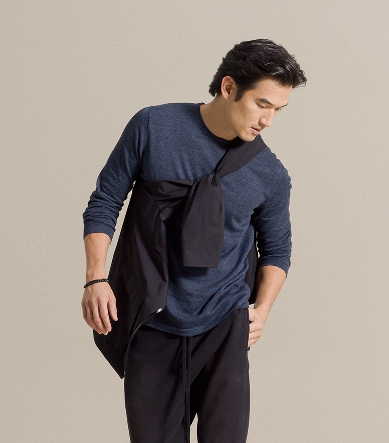 A male model poses in a blue shirt and black sweatpants.