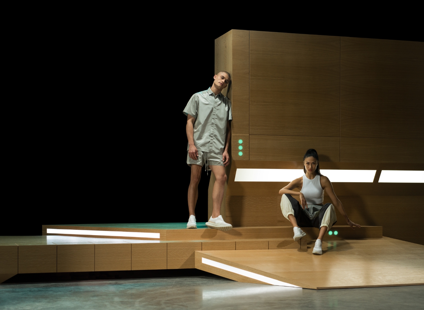 A man and woman pose on a wooden stage while wearing casual clothes and Magnanni sneakers.