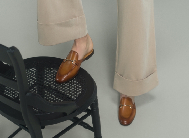 A woman steps onto a chair, showing off her Magnanni Stella V loafers in Cognac.