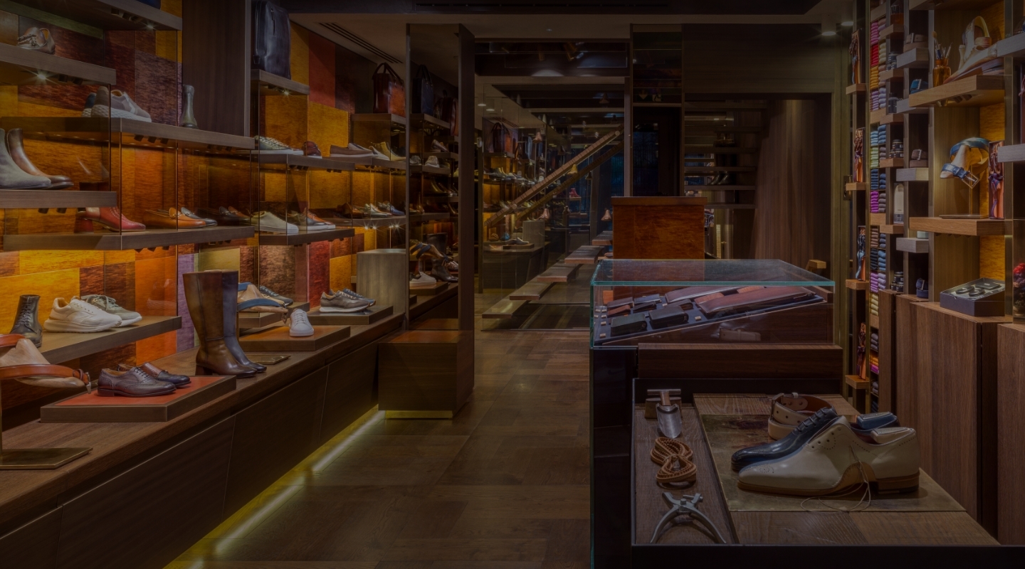 An image of the inside of the Magnanni store in Paris, featuring various shoes and belts along the wooden shelving.